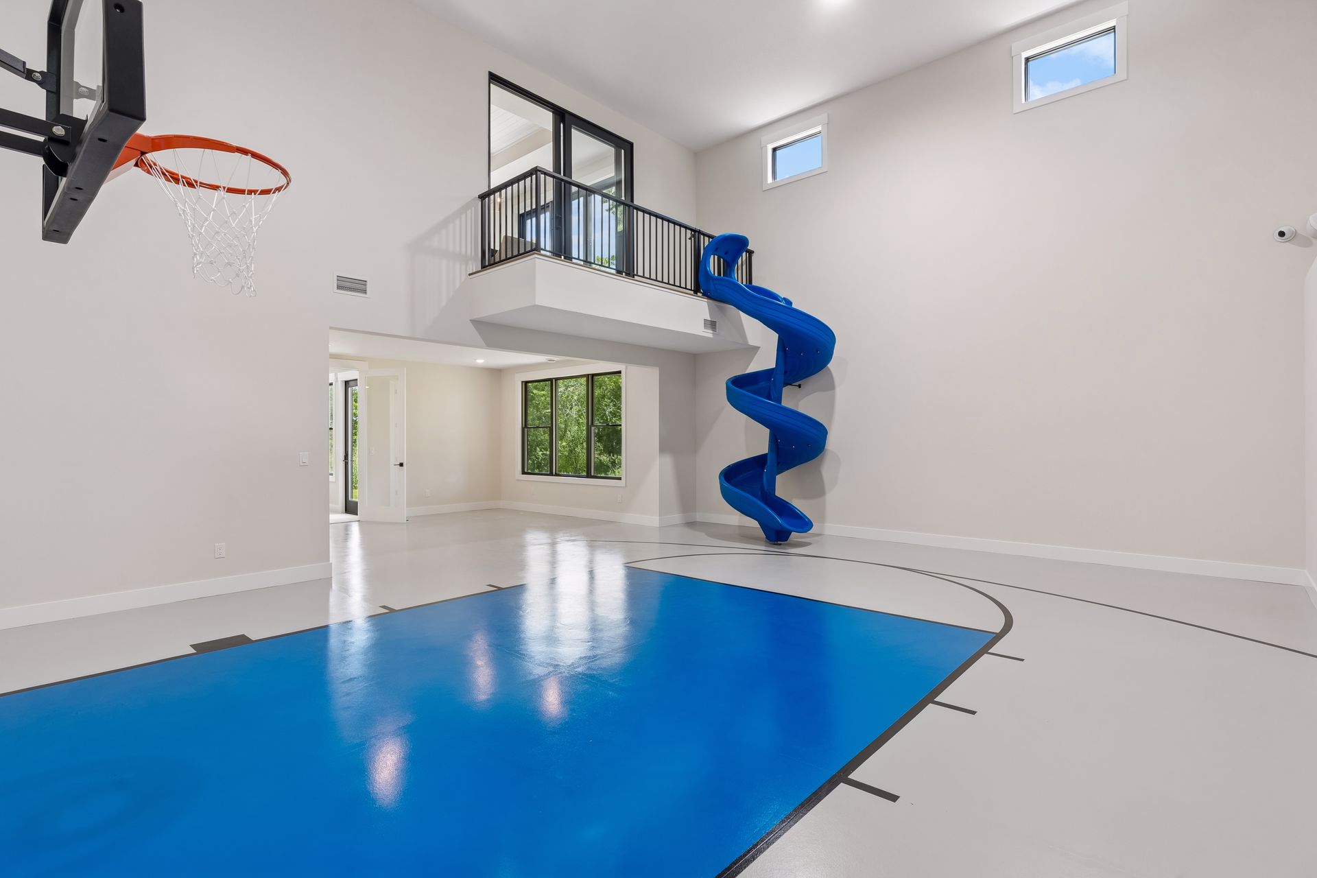 Two story indoor sport court with basketball hoop and blue spiral slide